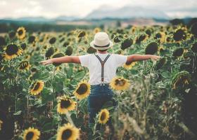 vista posteriore di un bambino felice nel campo dei girasoli foto