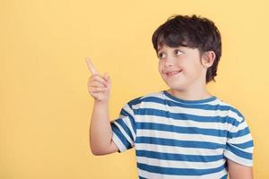 bambino sorridente che punta con la mano e il dito verso il lato con un'espressione felice foto