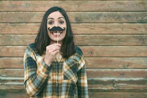 giovane donna divertente che tiene i baffi sul bastone foto