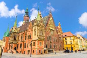 edificio gotico del vecchio municipio con guglia della torre dell'orologio sulla piazza del mercato di Rynek in ciottoli foto