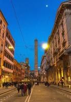bologna, italia molte persone camminano per la strada verso due torri medievali foto