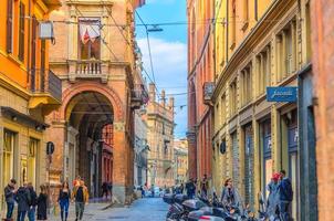 bologna, italia la gente sta camminando lungo la tipica strada italiana con tradizionali edifici colorati foto