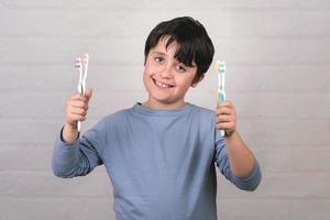 bambino felice che pulisce i denti con lo spazzolino da denti foto