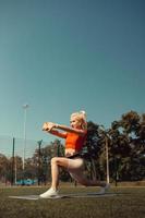 bella bionda che fa stretching sul prato di un campo da calcio foto