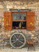 dettaglio finestra antica e ruota, sedia e ruota davanti alla facciata di un edificio antico foto