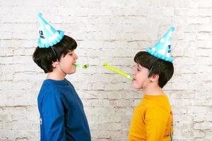 bambini divertenti con cappello da festa che soffia in un corno da festa foto