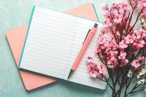 vista dall'alto del diario vuoto aperto con penna rosa, fiori di mandorlo e spazio per la copia foto