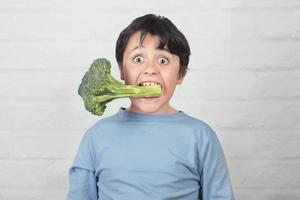 bambino felice con i broccoli in bocca foto