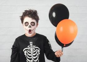 felice Halloween. bambino divertente in un costume da scheletro con palloncini colorati foto