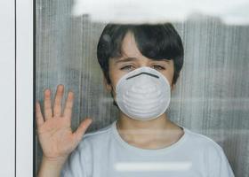 bambino messo in quarantena dalla pandemia di coronavirus con maschera medica foto