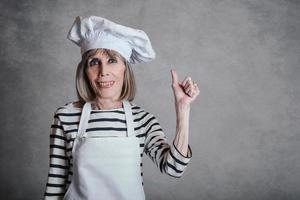 donna anziana sorridente con cappello da cuoco foto