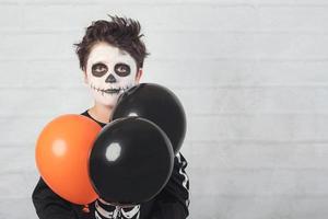felice Halloween. bambino divertente in un costume da scheletro con palloncini colorati. foto