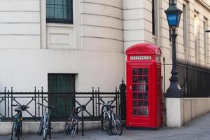 cabina telefonica britannica rossa e alcune biciclette. london street, senza persone foto