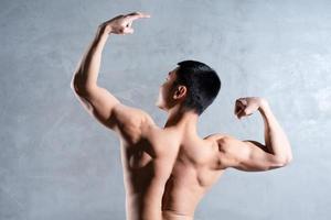 uomo asiatico muscoloso in posa su sfondo grigio foto