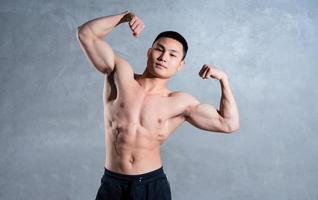 uomo asiatico muscoloso in posa su sfondo grigio foto