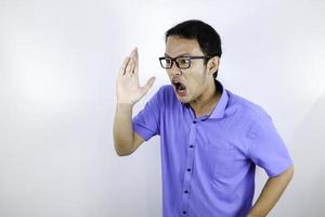 primo piano ritratto di un giovane uomo asiatico che grida facce forti e arrabbiate con il braccio in faccia isolato su bianco foto