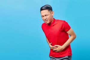 ritratto di giovane uomo asiatico malato con mal di stomaco problemi di salute diarrea disagio, costipazione nell'intestino isolato su sfondo blu foto