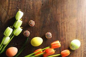 decorazione pasquale con uova fantasiose e palla di cioccolato arcobaleno e tulipani su sfondi di legno sopra foto