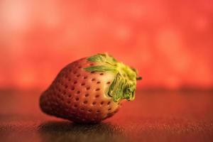 un primo piano di una singola fragola rossa su un tavolo foto