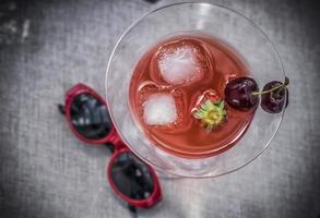 un bicchiere di cocktail rosso con frutta estiva foto