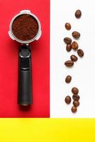 portafiltro per macchina da caffè espresso con caffè macinato e chicchi di caffè su sfondo bianco, rosso e giallo. foto