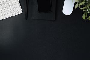 scrivania vista dall'alto con tastiera mouse e notebook su sfondo nero tavolo foto