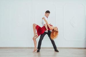 giovane bella donna in un vestito rosso e un uomo che balla, isolato su uno sfondo bianco. foto