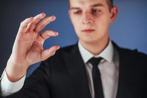 il giovane uomo d'affari in un vestito mostra la sua mano foto