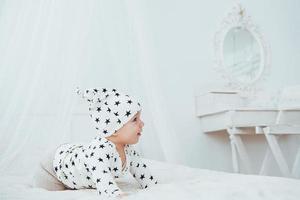 il neonato vestito con un abito bianco e stelle nere è un morbido letto bianco in studio foto
