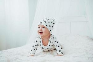 il neonato vestito con un abito bianco e stelle nere è un morbido letto bianco in studio foto