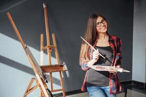 artista della giovane donna che dipinge un'immagine in studio foto