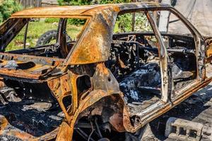 autovettura bruciata sulla strada di una zona disfunzionale foto