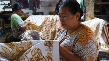 attività di realizzare batik, creare e progettare tessuto bianco utilizzando canting e cera sbattendo sul tessuto, pekalongan, indonesia, 7 marzo 2020 foto