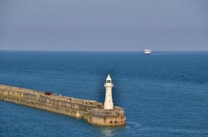 faro sul mare con nave foto