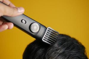 tagliare i capelli con un tagliacapelli su sfondo giallo foto