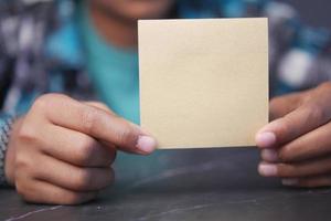 la mano dell'uomo tiene una nota adesiva da vicino foto