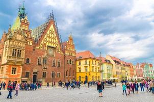 Wroclaw, Polonia, 7 maggio 2019 vecchio municipio con guglia della torre dell'orologio, edifici colorati e folla di molte persone turisti sulla piazza del mercato di ciottoli Rynek nel centro storico della città vecchia foto