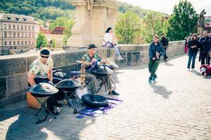 praga, repubblica ceca, 13 maggio 2019 i musicisti di strada stanno suonando i loro strumenti a tamburo e l'uomo sta ballando sul ponte pedonale di ciottoli charles karluv più sul fiume vltava foto