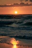 sole caldo giallo sulle onde del mare al cielo al tramonto panoramico, mare infinito alla luce solare calda al tramonto drammatico foto