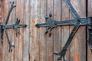 motivo forgiato su porta con elementi decorativi, vecchio ingresso vintage, massiccia porta di legno pesante della chiesa o della cattedrale. foto