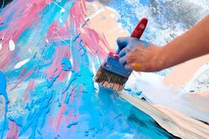 arte di espressione di pittura a goccia su tela con colori blu, rosa e beige, performance artistica dell'artista foto