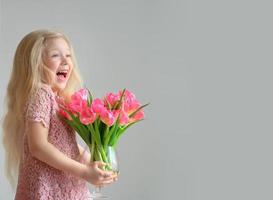 bambina ridente che tiene un vaso di tulipani foto