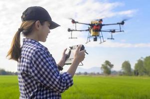 giovane agricoltore intelligente che controlla i droni che spruzzano fertilizzanti e pesticidi su terreni agricoli, innovazioni ad alta tecnologia e agricoltura intelligente foto