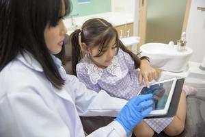 dentista femminile che spiega i raggi x dei denti a una bambina in clinica dentale, controllo dei denti e concetto di denti sani foto