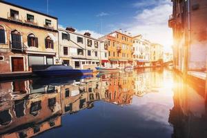 canale d'acqua verde con gondole e facciate colorate di vecchi edifici medievali al sole a venezia, italia. foto