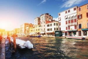 canale d'acqua verde con gondole e facciate colorate di vecchi edifici medievali al sole a venezia, italia. foto