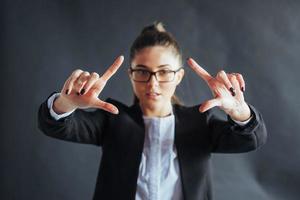 donna d'affari felice mostra il dito in alto, in piedi su uno sfondo nero in studio, amichevole, sorridente, concentrarsi a portata di mano. foto
