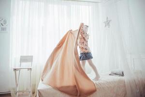 la bambina vuole avvolgersi in una coperta nella luce della camera da letto foto