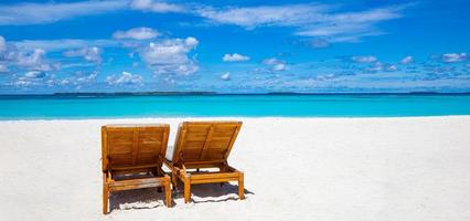 due sdraio sulla spiaggia di sabbia tropicale, panorama ideale per striscioni. bella spiaggia. sedie sulla spiaggia sabbiosa vicino al mare. turismo di concetto di vacanza di vacanza estiva. paesaggio tropicale ispiratore foto