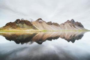 montagne incredibili riflesse nell'acqua al tramonto. stoksnes, Islanda foto